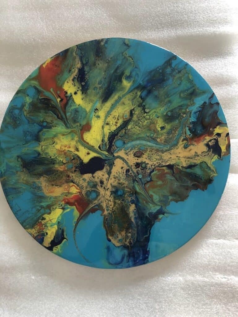 Art Abstrait Fluide : Peinture Circulaire Multicolore Peinture abstraite fluide sur canevas circulaire aux tourbillons turquoise, jaunes et rouges éclatants.