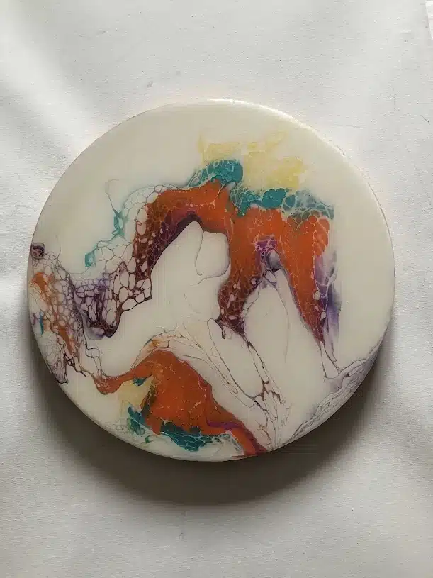Art fluide circulaire blanc aux motifs de cellules orange, bleu et violet sur fond neutre.