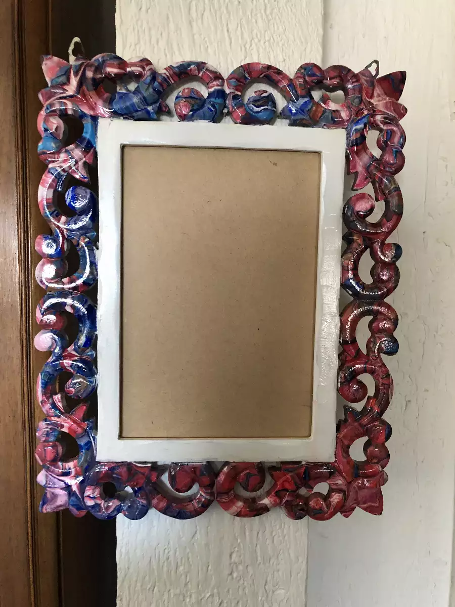 Cadre photo sculpté avec effet marbré rouge, bleu et blanc, bordure intérieure blanche sur un mur texturé.
