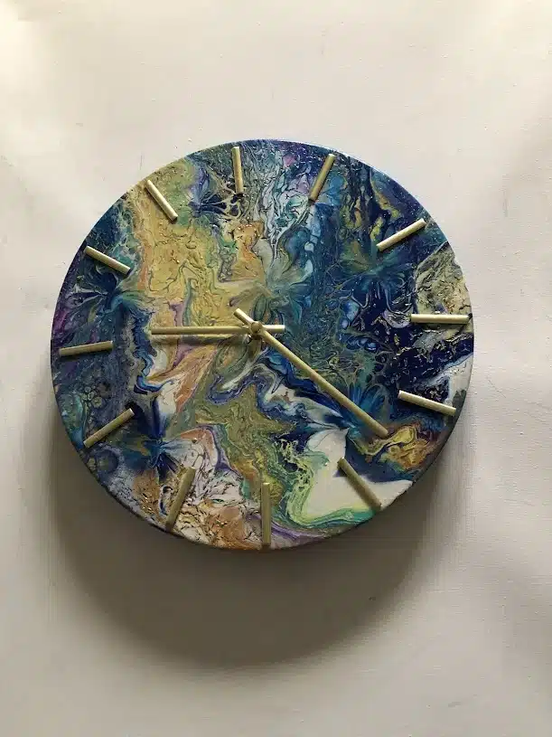 Horloge Murale Design Abstrait Bleu et Doré Moderne Horloge murale ronde au design fluide abstrait bleu et doré avec aiguilles métalliques sur fond blanc.