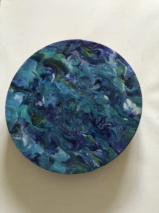 Peinture abstraite circulaire aux tourbillons bleus, turquoises et violets évoquant l'océan ou une nébuleuse cosmique.