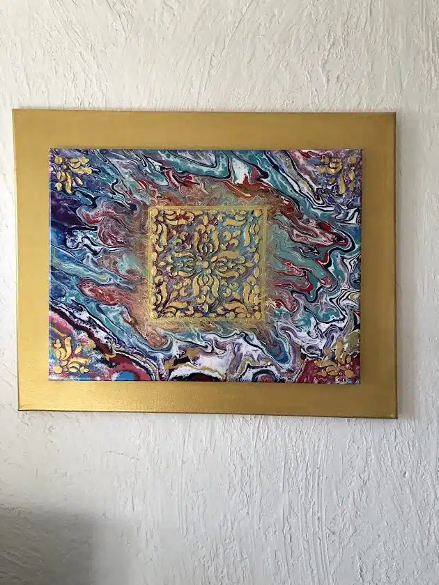 Peinture abstraite fluid art aux tourbillons bleus et rouges avec motif damassé doré central et cadre or.