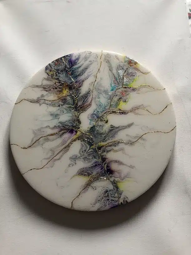 Peinture fluide circulaire aux nuances violettes et bleues avec des lignes dorées élégantes sur fond blanc.